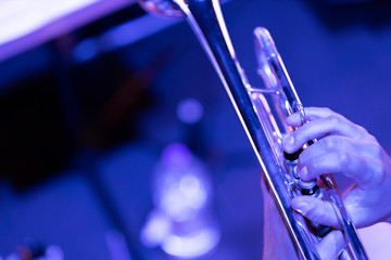 A musician playing a trumpet in blue stage lights