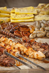 Barbecue fries in the coals. Meat and beef at the field kitchen festival. Fried meat on an wooden tray on the table. Different types of fried meat on the table. BBQ at the festival.