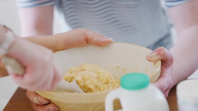 Close Up Of Young Downs Syndrome Couple Mixing Ingredients For Cake Recipe In Kitchen At Home