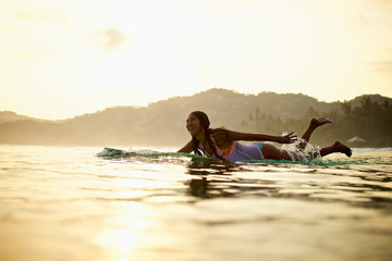 Happy female surfer paddling out in ocean on surfboard, Sayulita, Nayarit, Mexico
