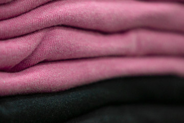 Fototapeta premium Warm clothing neatly folded on a store shelf. Sweatshirts, sweaters, jumpers, cardigans, hoodies, bobmers with piles on the shelf. Clothes storage. Size range.