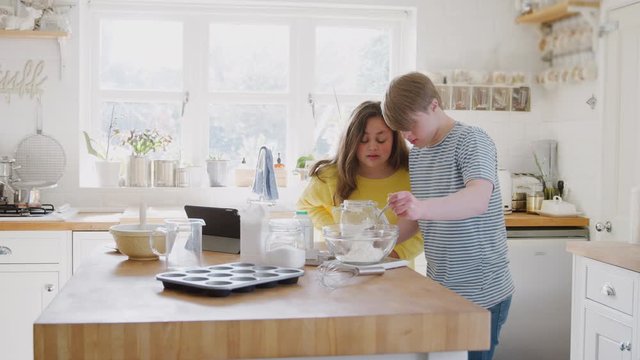 Young Downs Syndrome Couple Having Fun Baking In Kitchen At Home