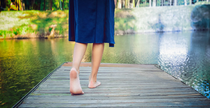 Young girl making a step bootlessly on the wooden pier and moving forward to the water. Select right way. Choose Your Own Path concept. Selective focus. Wide banner. Copy space.