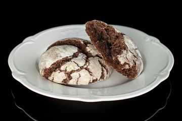 Group of one whole one half of baked chocolate brownie cookie on white plate isolated on black glass