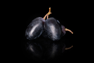 Group of three whole fresh black grape isolated on black glass