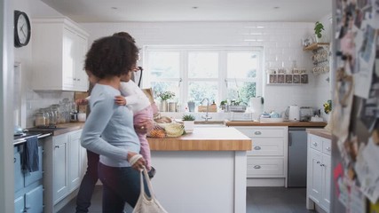 Family Returning Home From Shopping Trip Using Plastic Free Bags Unpacking Groceries In Kitchen