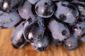 Lot of whole fresh black grape closeup on natural wood
