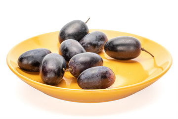 Group of eight whole fresh black grape on orange plate isolated on white background