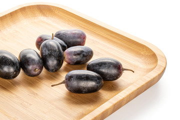 Fototapeta na wymiar Lot of whole fresh black grape on wooden square plate isolated on white background
