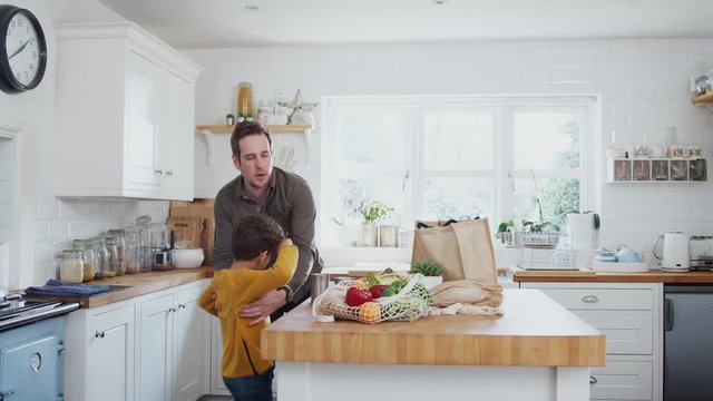 Father And Son Return Home From Shopping Trip Using Plastic Free Bags Unpacking Groceries In Kitchen