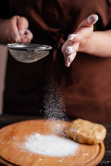 confectioner sprinkling flour on gingerbread dough