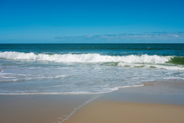 Obraz premium Ocean wave crashing on shoreline on a nearly cloudless day