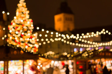 winter holidays and celebration concept - blurred christmas market in evening at town hall square...