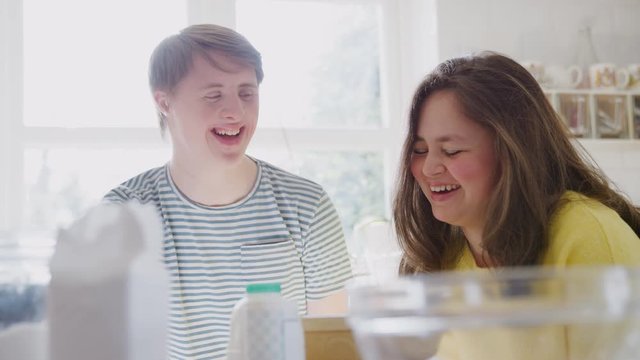Young Downs Syndrome Couple Having Fun Baking In Kitchen At Home