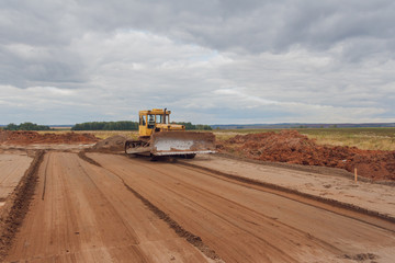  A bulldozer carries out earthwork at a construction site. Ground leveling for roads.