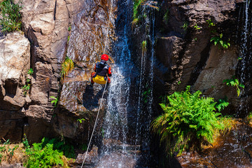 DESCENT OF WATERFALL WATERFALL WITH HANGING SCALE OF ROPES AND WATER FALLING ON ROCKS 