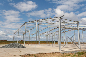 The metal structure of the new building against the blue sky in the autumn rays of the sun. Construction using metal.