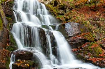 Fototapeta na wymiar Mountain waterfall in autumn forest