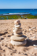 Fototapeta na wymiar STONES STACKED ON THE BEACH AND HORIZONTE WITH SEA AND BLUE SKY