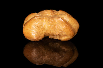 One whole baked golden profiterole isolated on black glass