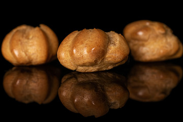 Fototapeta na wymiar Group of three whole baked golden profiterole isolated on black glass
