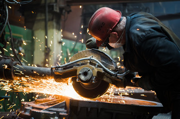 Worker grinding metal, metal grinding machine with sparks, metal sawing.