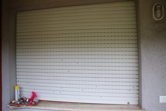 White protective shutters punctured by hail