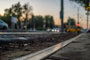 Tram tracks, rails close-up against a blurred city, cars during sunset