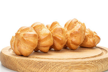 Group of five whole baked golden profiterole on bamboo plate isolated on white background