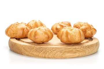 Group of six whole baked golden profiterole on bamboo plate isolated on white background