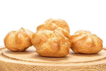 Group of four whole baked golden profiterole on bamboo plate isolated on white background