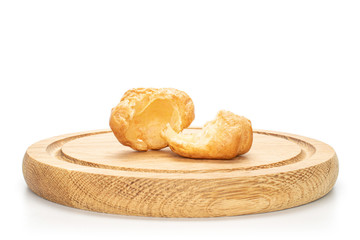 Group of two halves of baked golden profiterole on bamboo plate isolated on white background