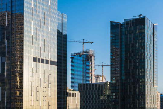 Modern skyscrapers in a downtown business district with cranes and new buildings under construction - concepts of development, progress, growth, economy, success