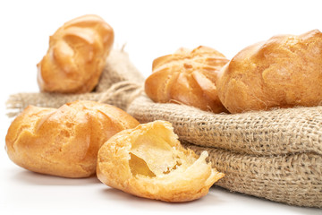 Group of four whole one half of baked golden profiterole with jute bag isolated on white background