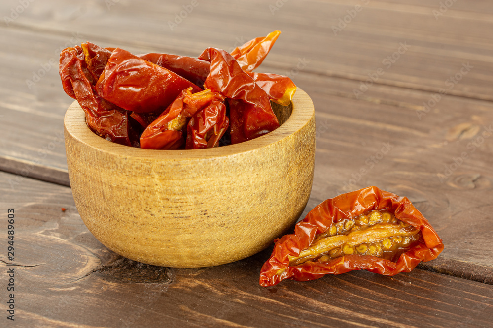 Wall mural lot of slices of dry red cherry tomato in wooden bowl on brown wood