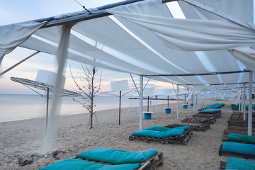 Fototapeta na wymiar Beach canopies with sun loungers by the sea
