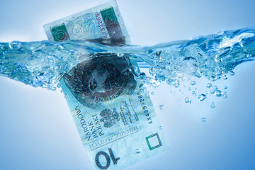 Money concept. Close up Polish currency Zloty sinking in water as symbol of global financial crisis...