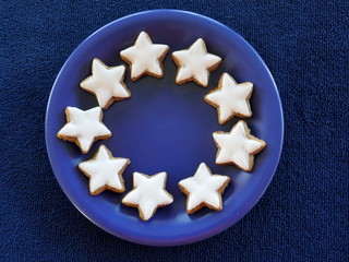  Christmas plate. Blue ceramic plate, decorated with home-baked cinnamon stars, isolated against a blue background.