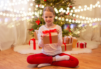 christmas, holidays and childhood concept - smiling girl with gift box at home