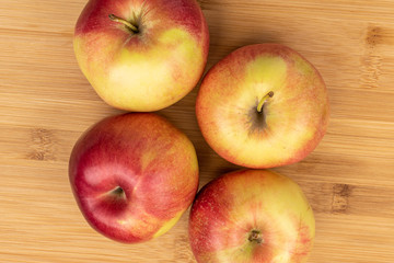 Group of four whole red apple jonagold flatlay on light wood