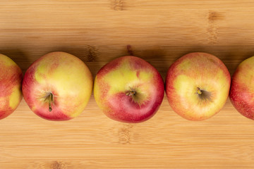 Group of five whole red apple jonagold flatlay on light wood