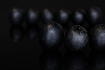 Lot of whole tasty black olive isolated on black glass
