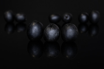 Lot of whole tasty black olive isolated on black glass