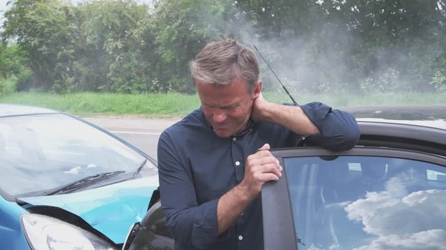 Male Driver With Whiplash Injury Getting Out Of Car After Crash 