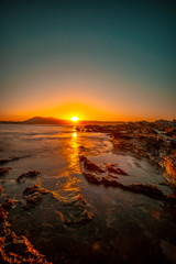 Obraz premium Last moments of the sun from the rocks of Hendaye on an orange sunset. France