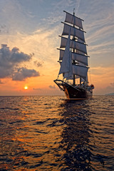 Beautiful sea at sunset and a sailing ship under white sails. Yachting