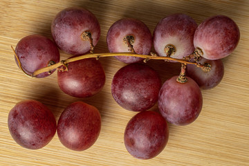 Lot of whole fresh purple grape rose flatlay on light wood