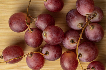 Lot of whole fresh purple grape rose flatlay on light wood