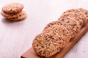 Cookies of sesame seeds, sunflower seeds and other spices on a wooden plate. Bright key