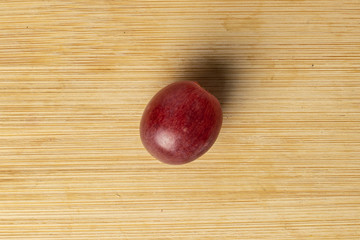 One whole fresh purple grape rose flatlay on light wood